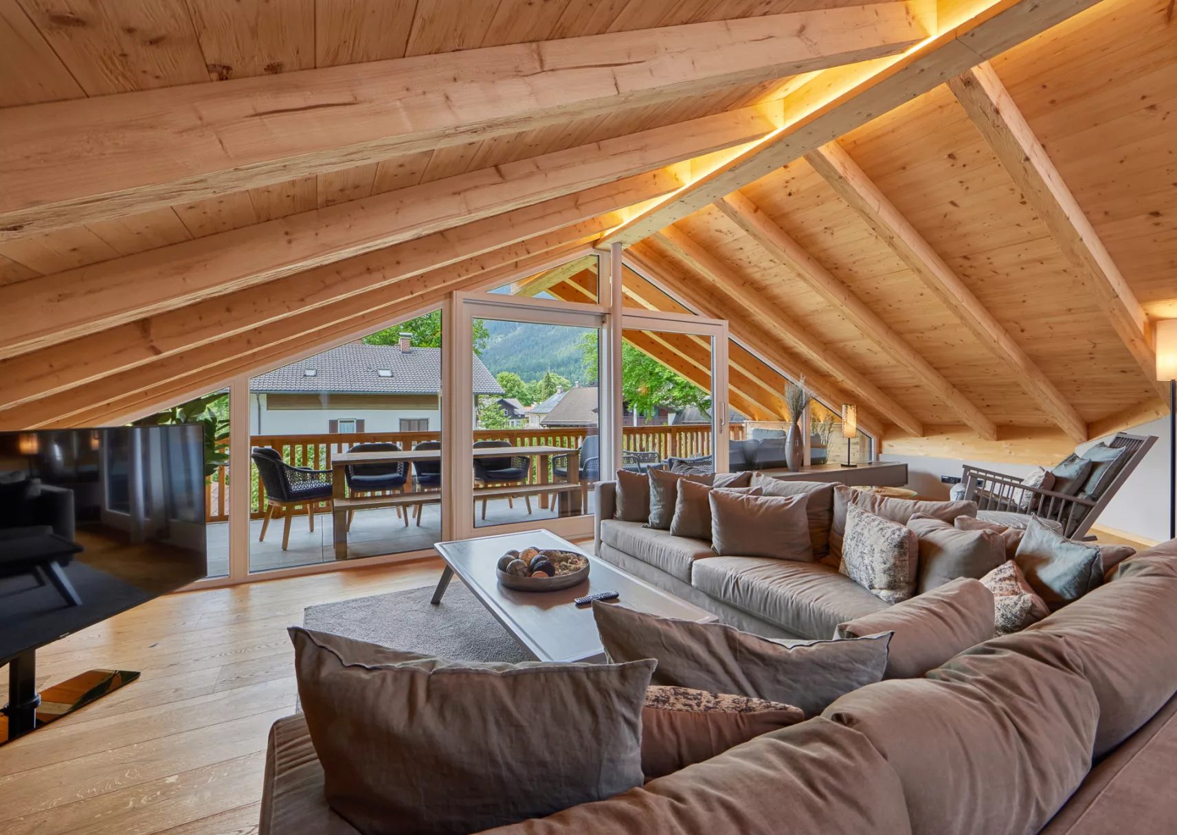 Wohnbereich unter Holzdach mit Sofa und Balkon in einer betreuten Ferienwohnung